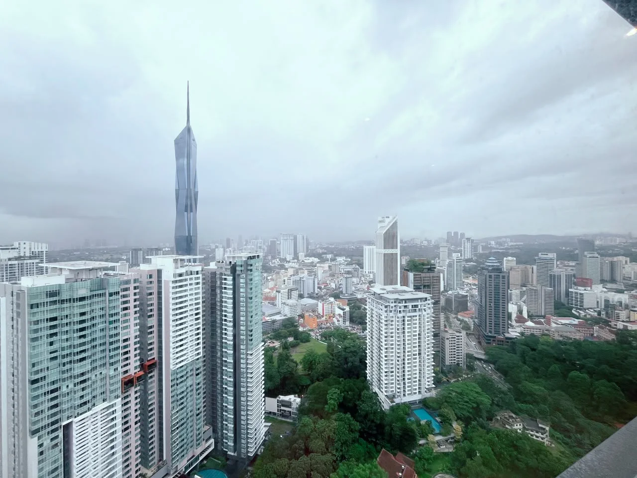 Exterior type: high-rise condominium; features: city skyline view, surrounded by greenery, modern architectural design, glass curtain wall, multiple high-rise buildings, urban landscape; style: modern.